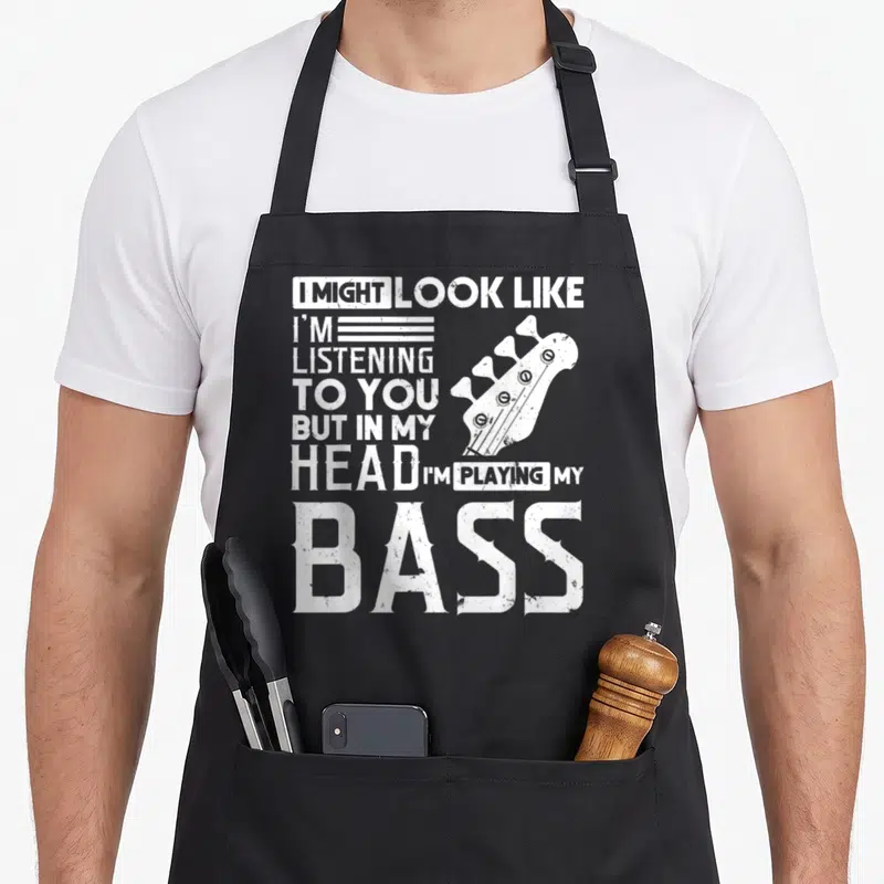 Tablier de cuisine noir avec inscription blanche sur la musique et illustration d'une tête de guitare basse.