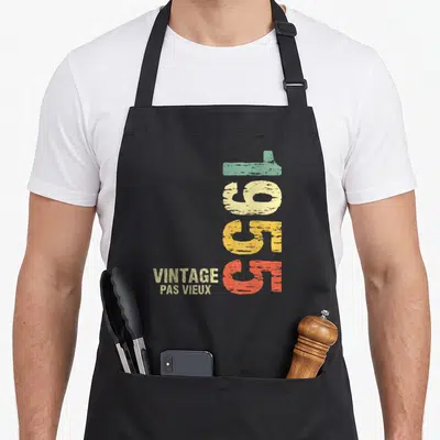 Tablier de cuisine noir avec inscription 70 vintage pas vieux en lettres colorées vertes jaunes et oranges sur fond uni.