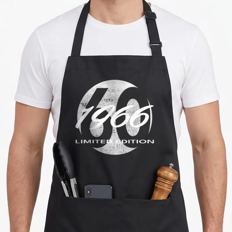 Tablier de cuisine noir avec l'inscription 1966 Limited Edition et un grand 60 en arrière-plan blanc texturé.