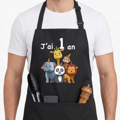 Tablier de cuisine noir avec cinq animaux de zoo mignons et le texte J'ai 1 an en blanc au-dessus.