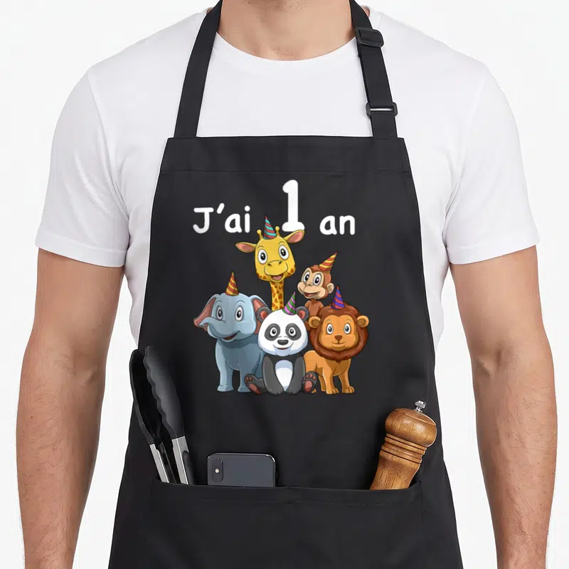 Tablier de cuisine noir avec cinq animaux de zoo mignons et le texte J'ai 1 an en blanc au-dessus.