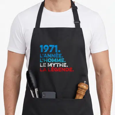 Tablier de cuisine noir avec inscription 1971 l'année l'homme le mythe la légende en typographie colorée.