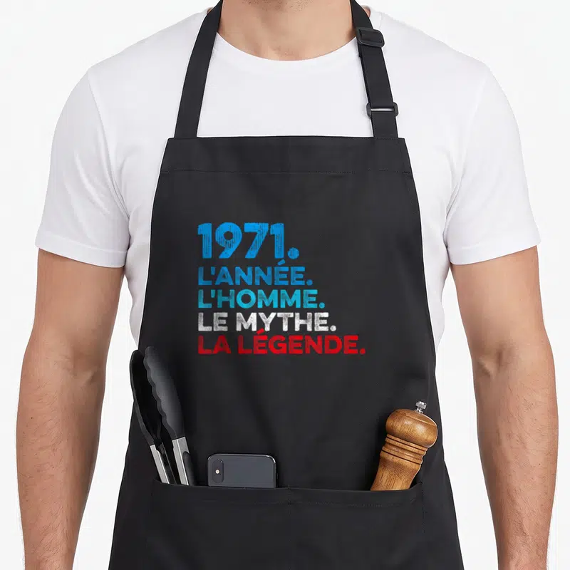 Tablier de cuisine noir avec inscription 1971 l'année l'homme le mythe la légende en typographie colorée.