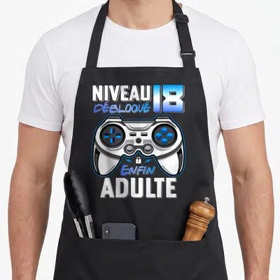 Tablier de cuisine noir avec illustration manette de jeu vidéo et texte Niveau 18 Débloqué Enfin Adulte en blanc et bleu.