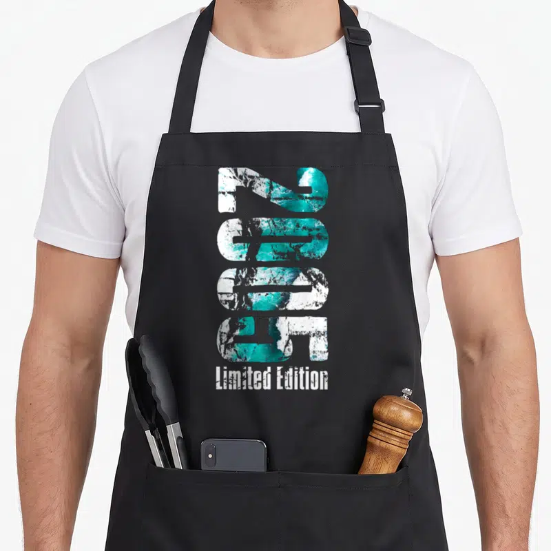 Tablier de cuisine noir avec le chiffre 2005 en texture turquoise et blanche et Limited Edition en dessous.