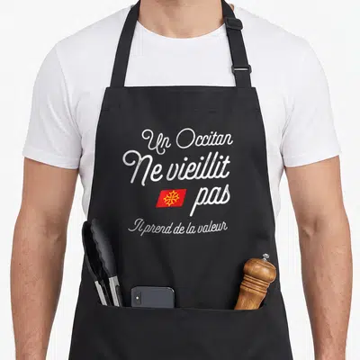 Tablier de cuisine noir avec inscription Un Occitan ne vieillit pas et drapeau occitan rouge et jaune au centre.
