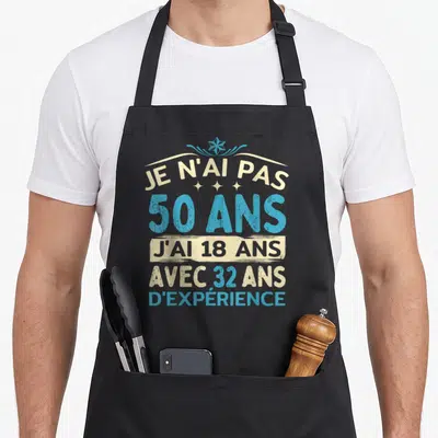 Tablier de cuisine noir avec inscription humoristique bleue et crème sur le thème des cinquante ans et de l'expériencee.