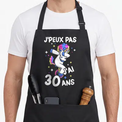 Tablier de cuisine noir avec licorne blanche aux cheveux roses et texte blanc Je peux pas j'ai 30 ans entouré d'étoiles.