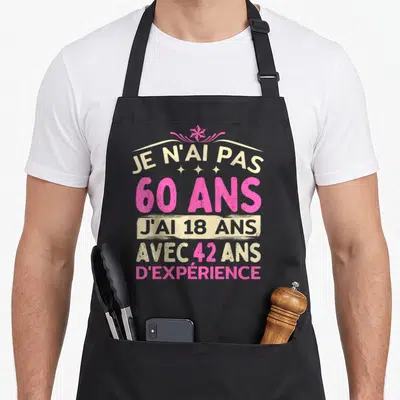 Tablier de cuisine noir avec inscription humoristique rose et crème sur le thème des 60 ans et de l'expérience accumulée.
