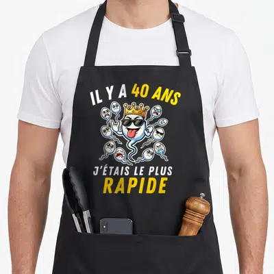 Tablier de cuisine noir avec illustration d'un spermatozoïde coiffé et des textes humoristiques sur 40 ans.