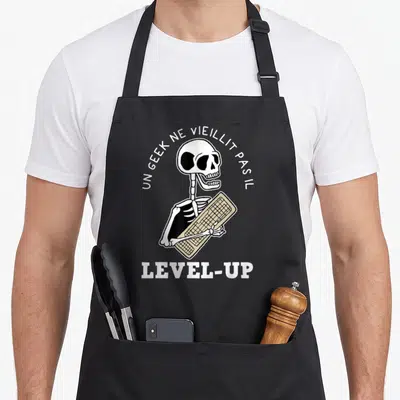 Tablier de cuisine noir avec squelette tenant un clavier beige et texte blanc arqué.