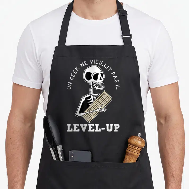 Tablier de cuisine noir avec squelette tenant un clavier beige et texte blanc arqué.