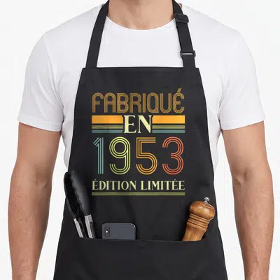 Tablier de cuisine noir avec inscription retro « Fabriqué en 1953 » « Édition Limitée » en couleurs pastel et orange.