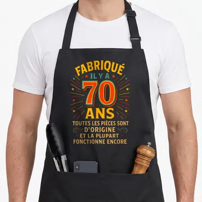 Tablier de cuisine noir avec inscription fabrique il y a 70 ans en typographie colorée vintage.