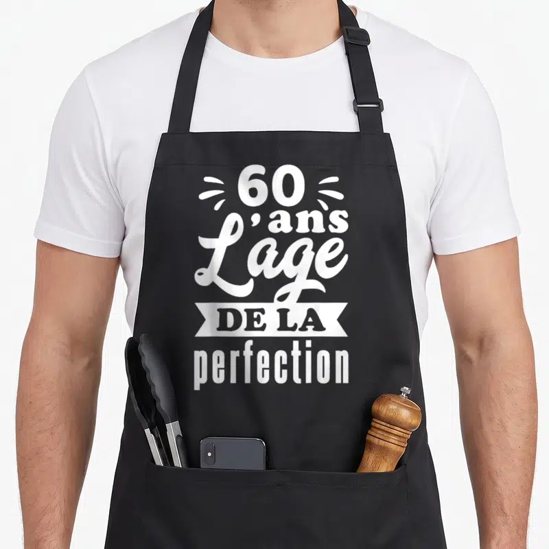 Tablier de cuisine noir avec l'inscription 60 ans l'âge de la perfection en typographie blanche stylisée.