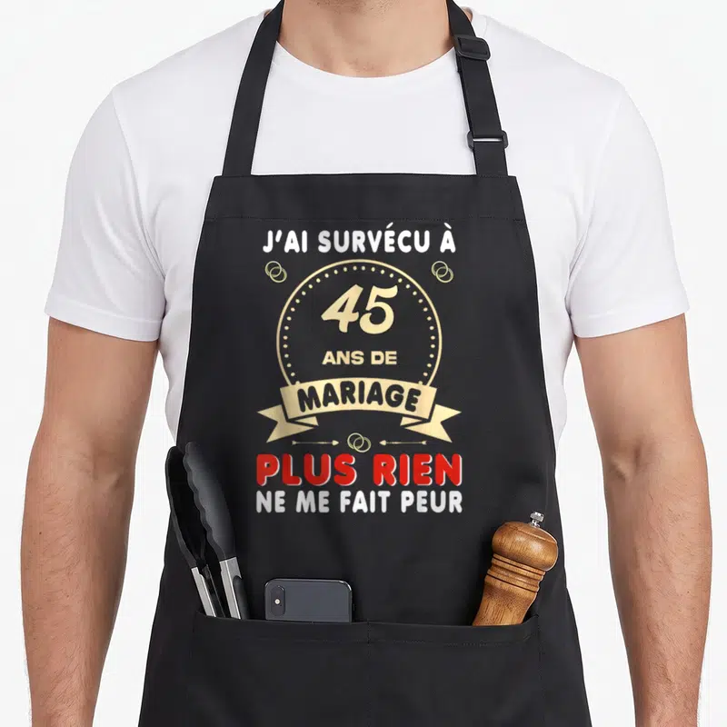 Tablier de cuisine noir avec l'inscription J'ai survécu à 45 ans de mariage plus rien ne me fait peur en lettres blanches et dorées.