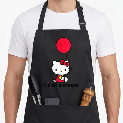 Tablier de cuisine noir avec Hello Kitty tenant un ballon rouge et la mention It's My anniversaire imprimée en bas.