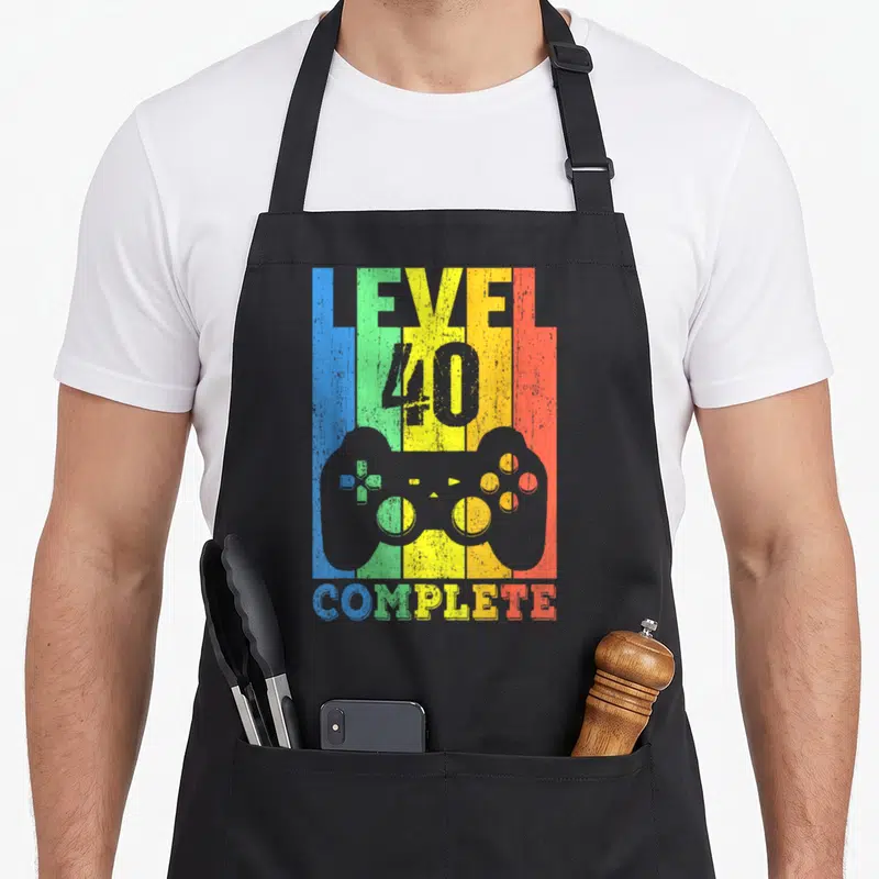 Tablier de cuisine noir avec illustration manette jeu vidéo et texte Level 40 Complete multicolore