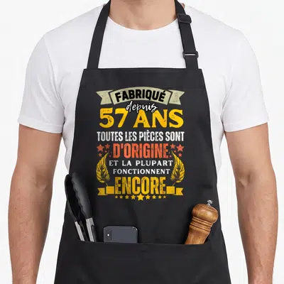 Tablier de cuisine noir avec inscription humoristique sur le thème des 57 ans et mécanisme d'origine.