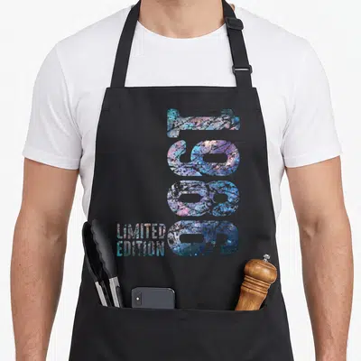 Tablier de cuisine noir avec le chiffre 1986 et Limited Edition en motifs numériques irisés bleus et roses.
