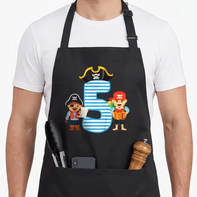 Tablier de cuisine noir avec un grand chiffre 5 bleu, deux pirates et un cadeau coloré imprimé au centre.