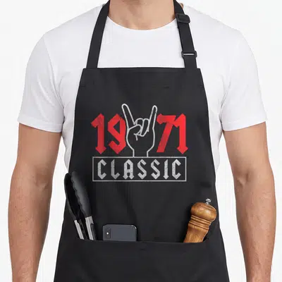 Tablier de cuisine noir avec motif 1971 Classic Rock et main faisant le signe des cornes en blanc et rouge.