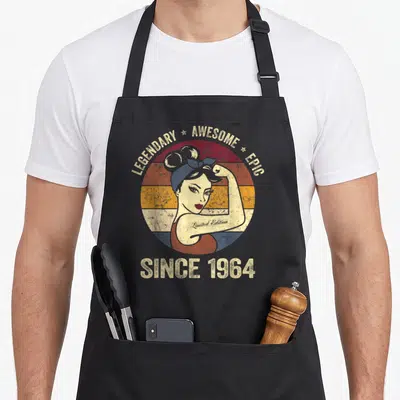 Tablier de cuisine noir avec illustration vintage d'une femme musclée et texte Since 1964.