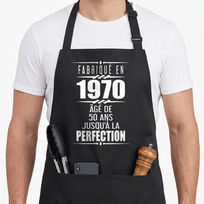 Tablier de cuisine noir avec inscription blanche « fabriqué en 1970 » âgé de 50 ans jusqu'à la perfection ornée de motifs décoratifs.