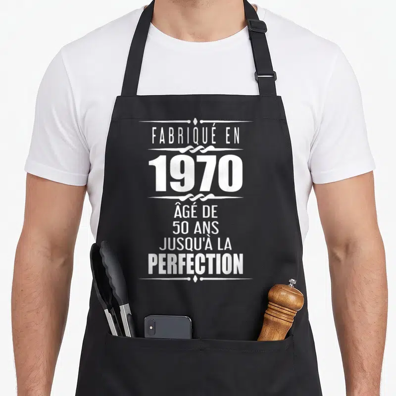 Tablier de cuisine noir avec inscription blanche « fabriqué en 1970 » âgé de 50 ans jusqu'à la perfection ornée de motifs décoratifs.