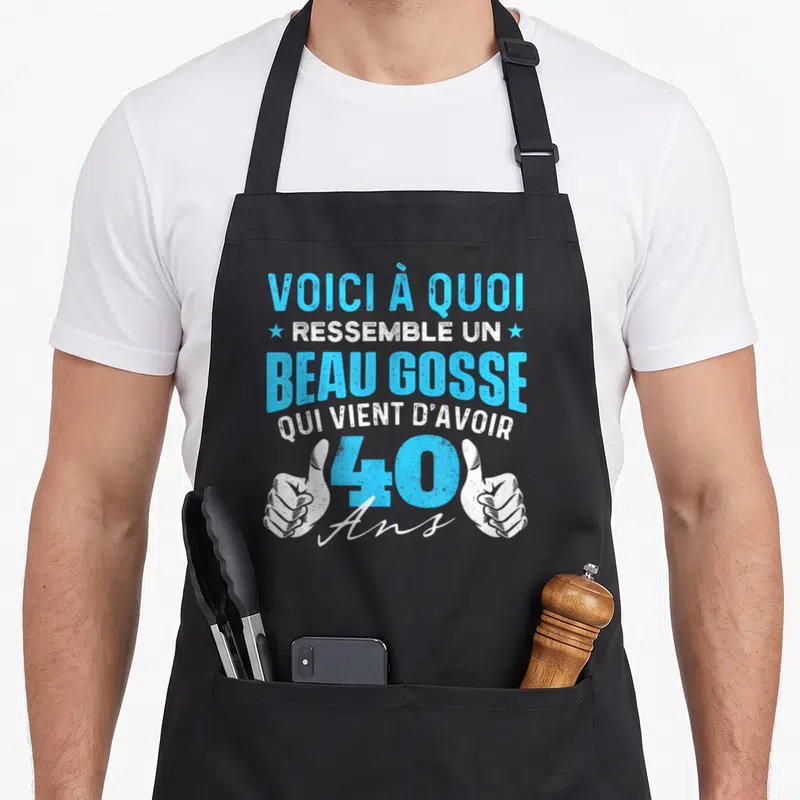 Tablier de cuisine noir avec inscription voici à quoi ressemble un beau gosse qui vient d'avoir 40 ans et deux poings levés.