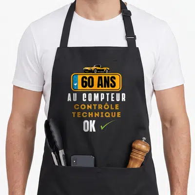 Tablier de cuisine noir avec plaque orange 60 ans au compteur contrôle technique ok et voiture jaune.