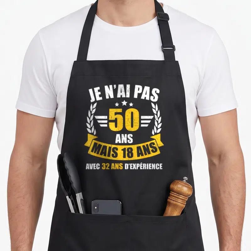 Tablier de cuisine noir avec un motif typographique blanc et jaune citant l'âge de 50 ans et 18 ans.