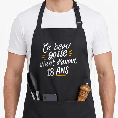 Tablier de cuisine noir avec inscription Ce beau gosse vient d'avoir 18 ans en blanc et orange.
