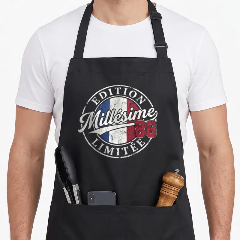 Tablier de cuisine noir avec logo circulaire Édition Millésime 86 Limitée sur fond tricolore.