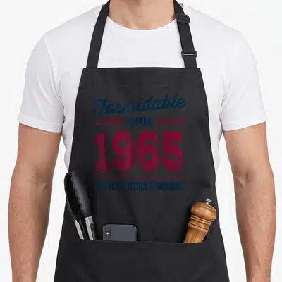 Tablier de cuisine noir avec inscription Formidable depuis 1965 et toutes pièces d'origine en typographie vintage rouge et bleue.