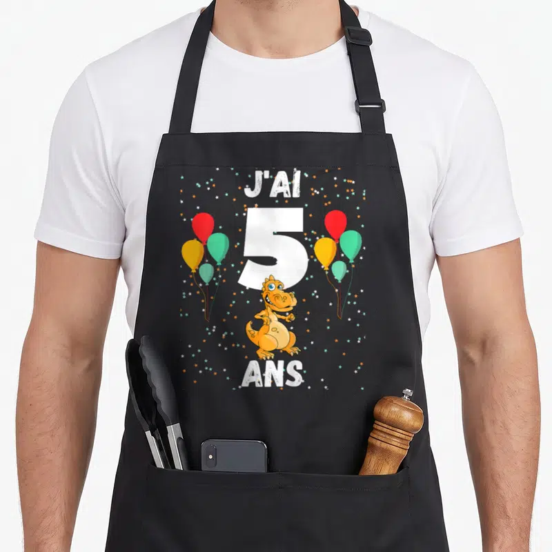 Tablier de cuisine noir avec dinosaure orange, ballons colorés et texte J'ai 5 ans.