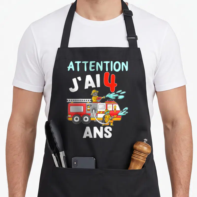 Tablier de cuisine noir avec un camion rouge, des pompiers et le texte Attention j'ai 4 ans imprimé au centre.