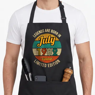 Tablier de cuisine noir avec motif circulaire vintage coloré affichant July 1982 et Vintage Limited Edition.