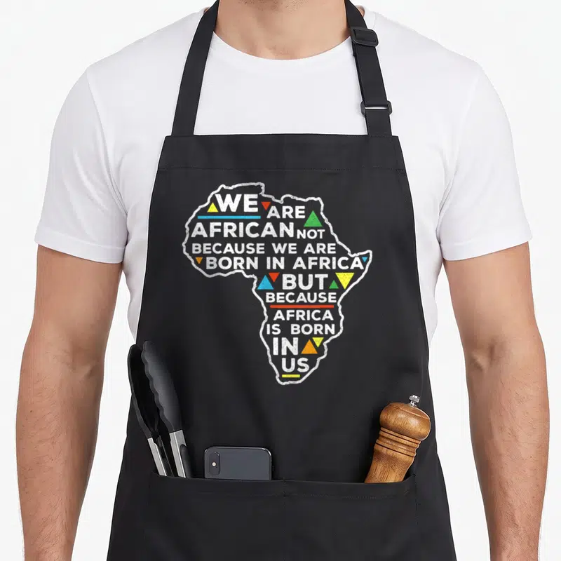 Tablier de cuisine noir avec une carte d'Afrique stylisée et un texte bilingue sur les racines et l'identité africaine.