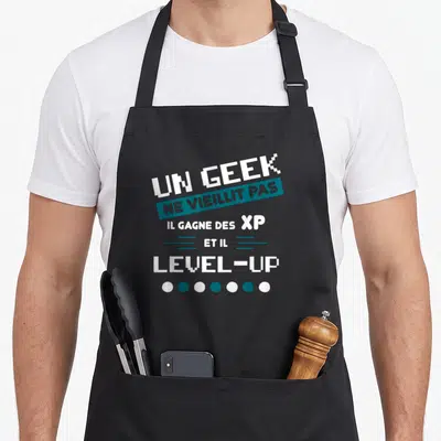 Tablier de cuisine noir avec un design pixel art blanc et bleu portant une citation humoristique sur le gaming.