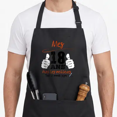 Tablier de cuisine noir avec l'inscription Mes 18 ans et deux mains faisant des pouces levés en blanc.