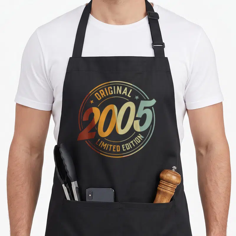 Tablier de cuisine noir avec un logo circulaire multicolore affichant 2005 Original Limited Edition en typographie rétro.
