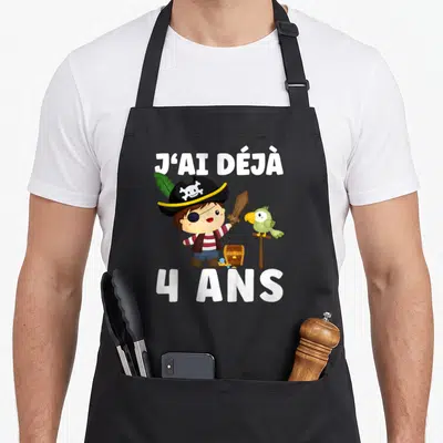 Tablier de cuisine noir avec un petit pirate et l'inscription J'ai déjà 4 ans en grosses lettres blanches.