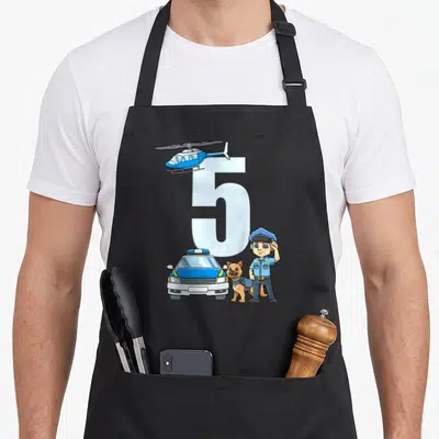 Tablier de cuisine noir avec un grand chiffre 5, une voiture de police bleue, un hélicoptère et un policier saluant avec son chien.