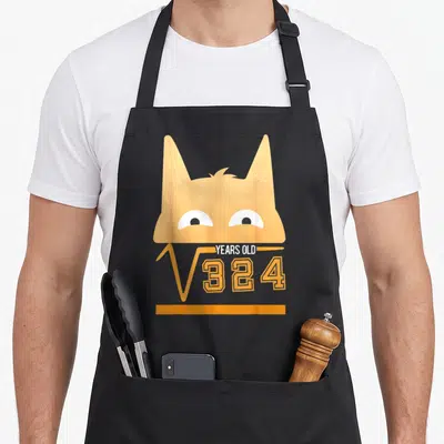 Tablier de cuisine noir avec tête de chat orange et inscription racine carrée de 324 ans 18 ans.