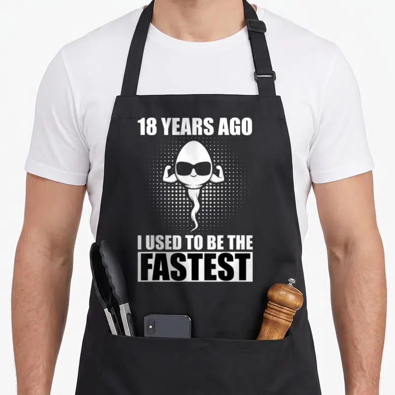 Tablier de cuisine noir avec un spermatozoïde musclé portant des lunettes de soleil et du texte en anglais.