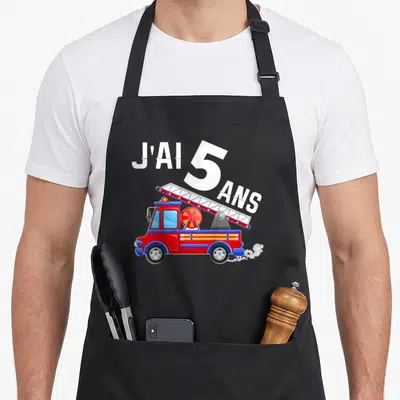 Tablier de cuisine noir avec un camion de pompiers rouge, une échelle et l'inscription J'ai 5 ans en blanc.