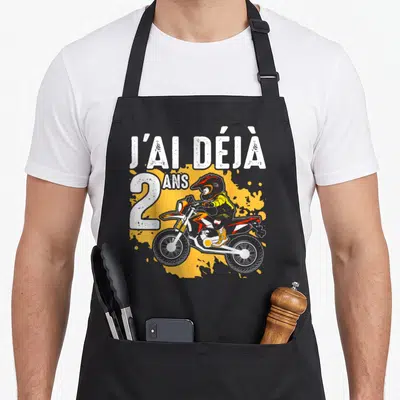 Tablier de cuisine noir avec illustration de moto cross et texte J'ai déjà 2 ans en blanc et orange.