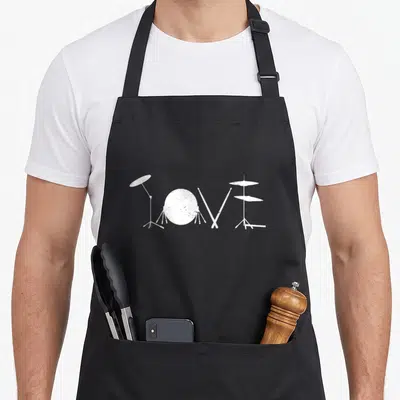 Tablier de cuisine noir avec le mot Love dessiné en instruments de batterie blancs et baguettes croisées.