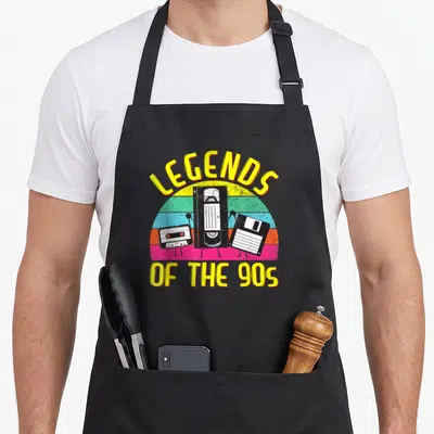 Tablier de cuisine noir avec cassette VHS et disquette aux jambes sur fond coloré arc-en-ciel